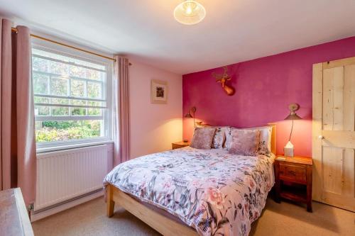 ein Schlafzimmer mit einem Bett mit einer lila Wand in der Unterkunft Tail End Cottage in Rye