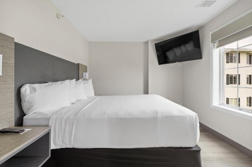 a bedroom with a white bed and a tv on the wall at GrandStay Residential Suites Rapid City in Rapid City