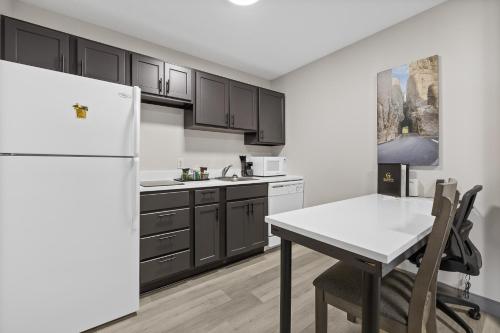 a kitchen with a white refrigerator and a table at GrandStay Residential Suites Rapid City in Rapid City