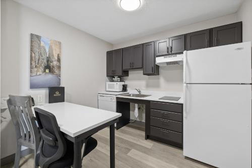 a kitchen with a white refrigerator and a table at GrandStay Residential Suites Rapid City in Rapid City