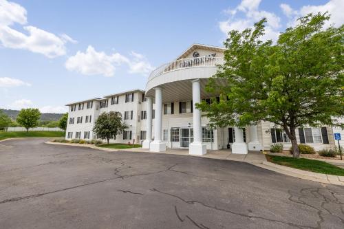 a large white building with a tree in front of it at GrandStay Residential Suites Rapid City in Rapid City