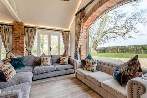 a living room with couches and a large window at The Cowshed - Haceby in Haceby
