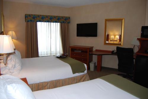 a hotel room with two beds and a desk with a mirror at Holiday Inn Express Hotel & Suites Auburn Hills by IHG in Auburn Hills