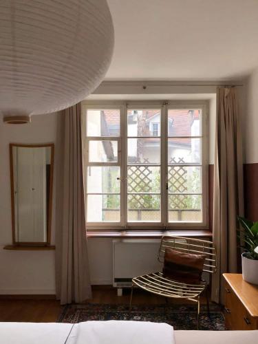 a bedroom with a window and a chair in front of it at Unesco Heritage & Steps To Bern's Sites! in Bern