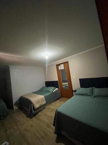 a bedroom with two beds and a door in it at Hotel Pousada do Mel in Gramado