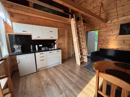 a kitchen with white cabinets in a wooden cabin at Leśny Zakątek - Mazury - Warmia - jezioro Dadaj in Ramsowo