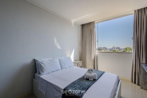 a bedroom with a bed and a large window at Apto c/ Churrasqueira a 240m da Praia LUP0302 in Itajubá