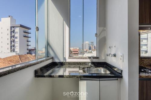 a bathroom with a sink and a large window at Apto c/ Churrasqueira a 240m da Praia LUP0302 in Itajubá
