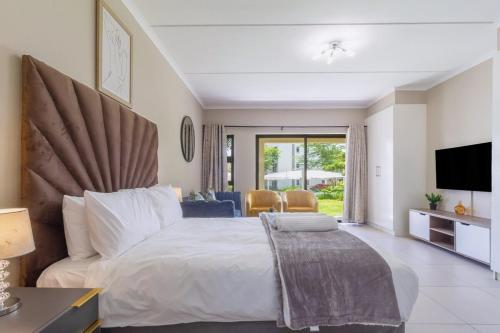 Un dormitorio con una cama grande y un televisor. en AlimamaSpaces - The View Studio, en Fourways