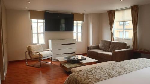 a hotel room with a bed and a couch and chair at Hotel Portón de la Cabrera in Bogotá