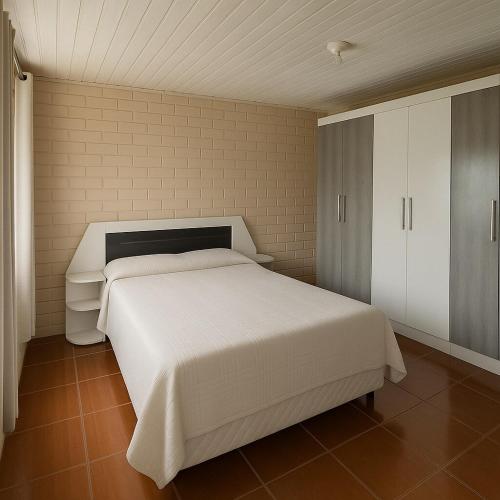 a bedroom with a white bed and a white cabinet at Casa Espaçosa 3quartos Piscina Churrasqueira Estacionamento in Canoas