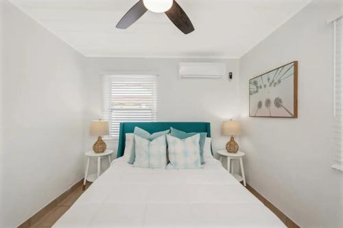 a white bedroom with a large bed with two tables at Mermaid Tropical Villa in Largo