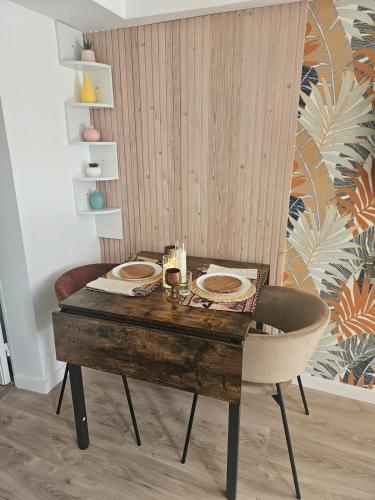 a wooden table with two plates on it with a chair at Maison Ethno Chic proche de Paris et d'Orly in Morangis