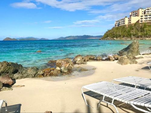a beach with two lounge chairs and the ocean at Penthouse Luxury With Ocean Views Resort Pools in East End