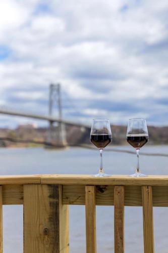 two glasses of red wine sitting on a wooden railing at Hudson Escape W Hot Tub Bridge View in Highland