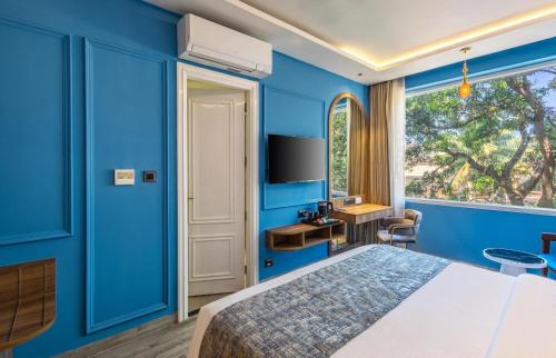 a blue bedroom with a bed and a window at The Boho Calangute Goa in Calangute