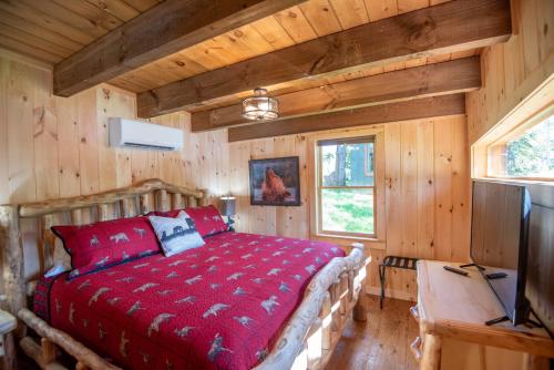 a bedroom with a red bed in a wooden cabin at 1 Mile to Downtown West Jefferson Camping Cabin #1 in West Jefferson