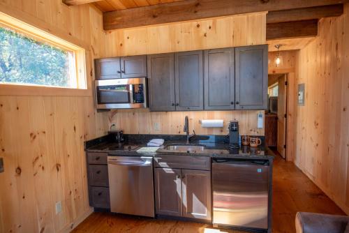 a kitchen with stainless steel appliances in a wooden cabin at 1 Mile to Downtown West Jefferson Camping Cabin #4 in West Jefferson