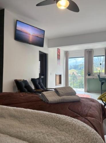 a bedroom with two beds and a tv on the wall at Pousada Recanto da Cascata in Águas de Lindóia