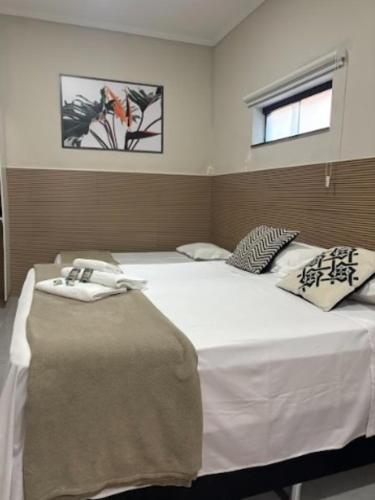 a bedroom with a large white bed with two pillows at Pousada Recanto da Cascata in Águas de Lindóia