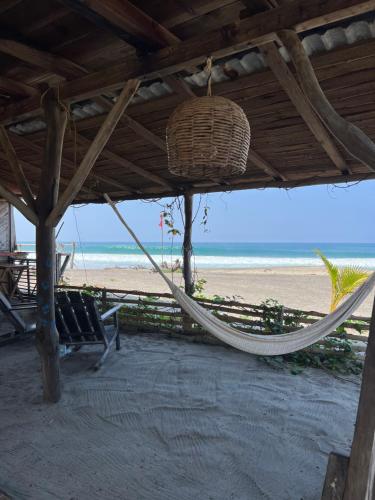 a hammock on a beach with a view of the ocean at Casa Momento - Retiro frente al mar con Starlink en Ventanilla in Zapote