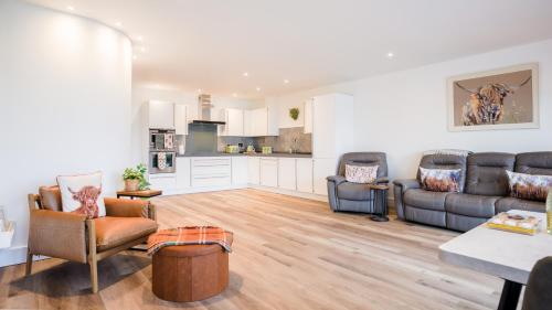 ein Wohnzimmer mit Sofas und eine Küche in der Unterkunft Vū by the Bridge, Inverness City Centre in Inverness