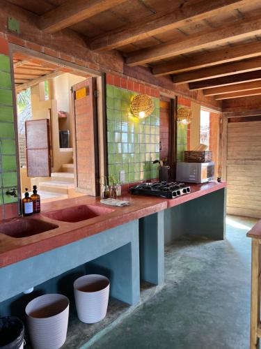 a kitchen with a counter with two sinks and a stove at Casa Momento - Retiro frente al mar con Starlink en Ventanilla in Zapote