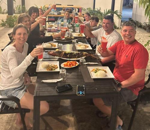 a group of people sitting at a table with food at Sunny Beach Thoddoo in Thoddoo