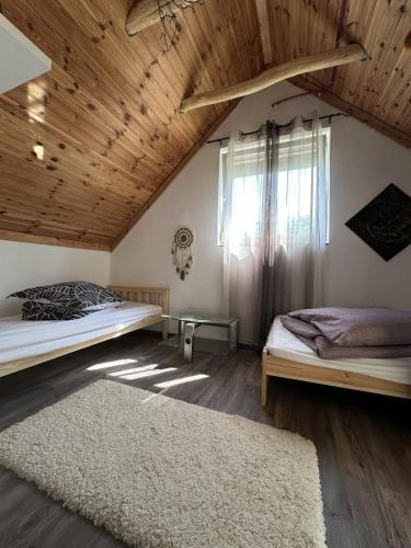 two beds in a room with a wooden ceiling at Non stop apartman in Kaposvár
