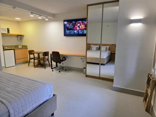 Un dormitorio con una cama y una mesa y una cocina. en Quarto 5 estrelas no Comfort Suites!, en Brasilia