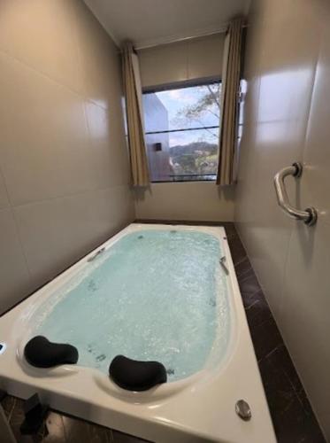 a bath tub in a bathroom with a window at Pousada Recanto da Cascata in Águas de Lindóia