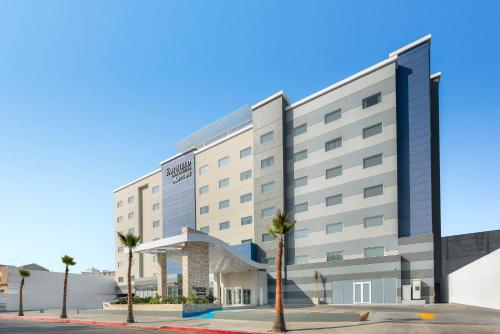 a large building with palm trees in front of it at Fairfield Inn & Suites by Marriott Tijuana in Tijuana