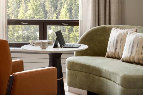 a living room with a chair and a table with a laptop at Fairmont Château Lake Louise in Lake Louise