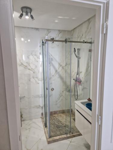a shower with a glass door in a bathroom at Staycation Yakout in Mansouria