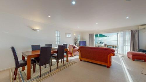 a living room with a dining table and chairs at Sunsets by the Beach Waterfront Sleeps 8 in Te Puru