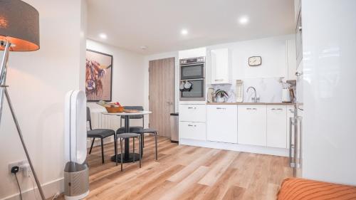 Stā by The Bridge, Inverness City Centre في إينفيرنيس: مطبخ مع خزائن بيضاء وطاولة وكراسي