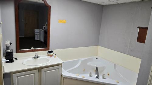 a bathroom with a tub and a sink and a mirror at Swiss Village Inn in Eureka Springs