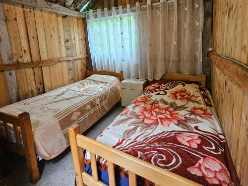 a bedroom with two beds in a wooden cabin at Kafe Pojana in Tropojë