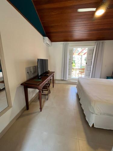 a bedroom with a bed and a desk with a computer at Pousada Corsario Buzios in Búzios