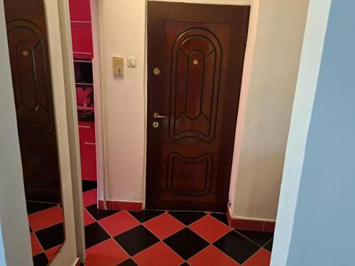 a brown door in a hallway with a checkerboard floor at Apartament Saraol in Deva