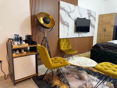 a room with yellow chairs and a bed and a television at Golden Hill Palace in Novi Pazar