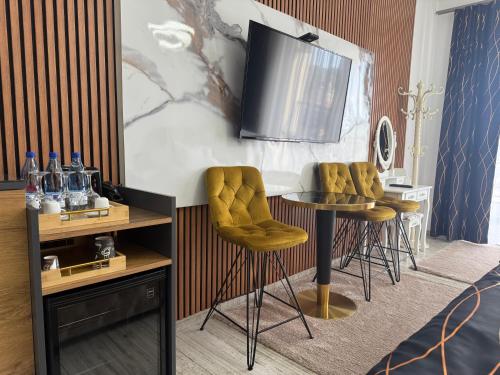 a room with a table with yellow chairs and a television at Golden Hill Palace in Novi Pazar