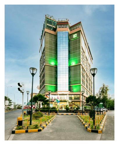 a large building with green windows on a street at Holiday Inn Dar Es Salaam by IHG in Dar es Salaam