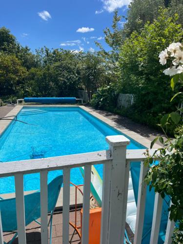 a swimming pool next to a white rail at Rose Cottage in Puketapu