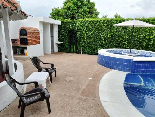 un patio con sillas y una piscina con sombrilla en Villa luxoa, en Ricaurte