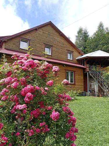 ein Haus mit rosa Blumen davor in der Unterkunft Магурчик in Worochta