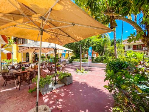 a patio with tables and chairs and an umbrella at LOS CORALES Resort VILLAS & Apartments WIFI BEACH Club & SPA in Punta Cana