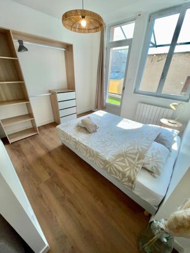 a bedroom with a bed and two windows at Appartment Mal coiffé in Moulins