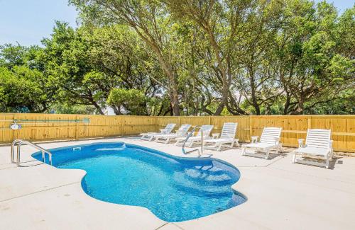 a swimming pool with chairs and a fence at Sounds Great! in Duck