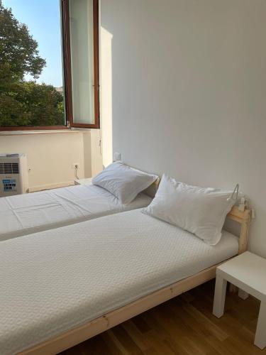 two beds in a room with a window at Livorno 3X3 in Livorno